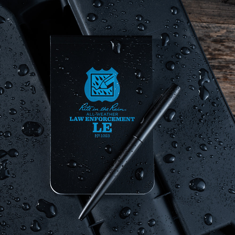 Black notebook with blue text and logo on a wet surface