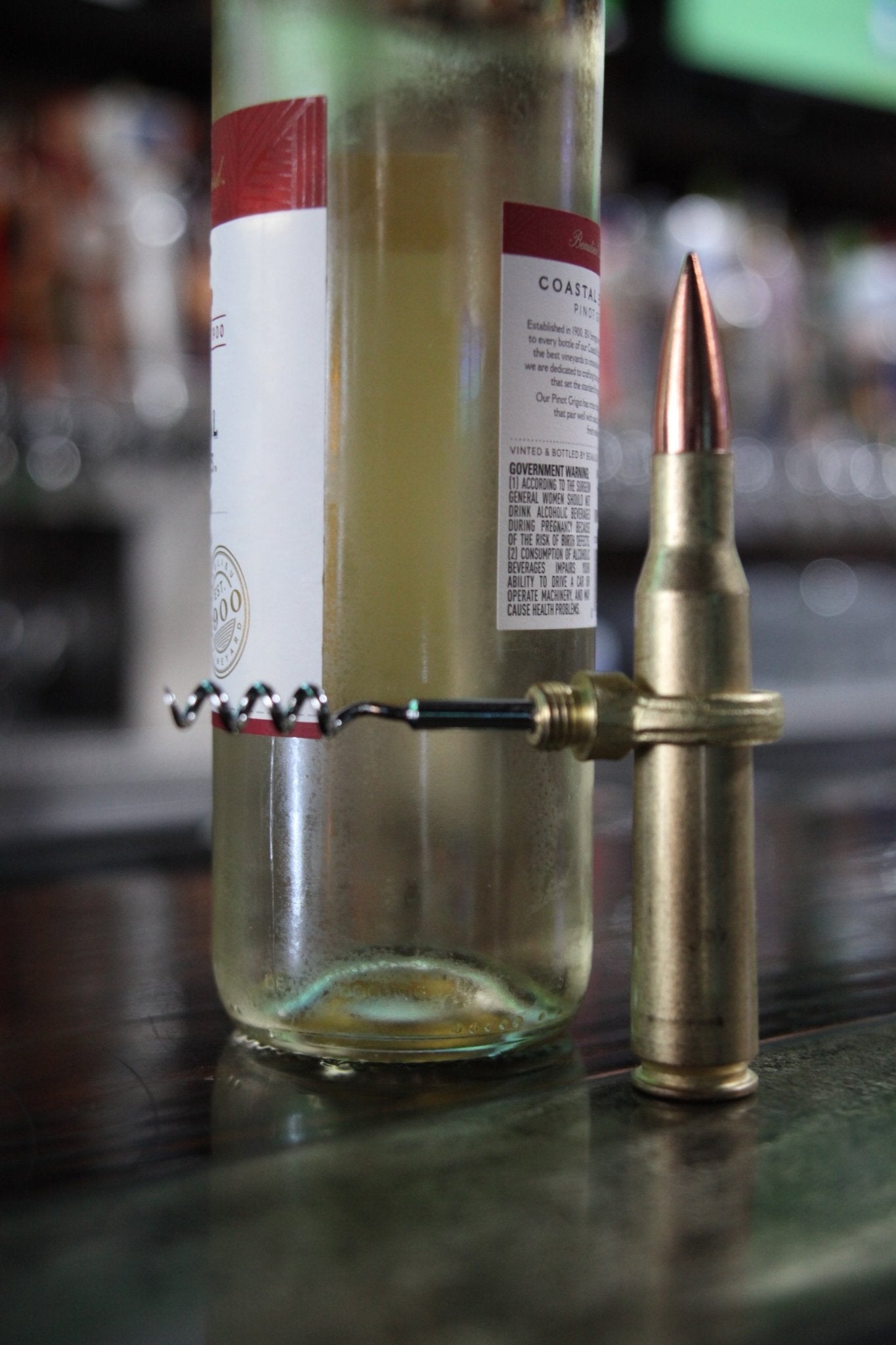 Bottle with a brass bullet-shaped bottle opener on a bar counter