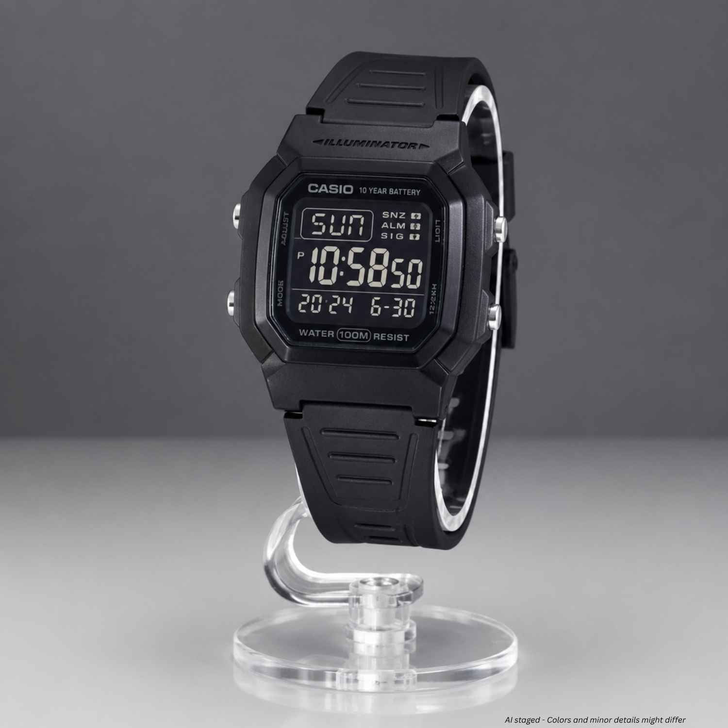 A black Casio digital wristwatch with a matching black strap, displayed upright on a clear acrylic stand against a dark gray studio background.