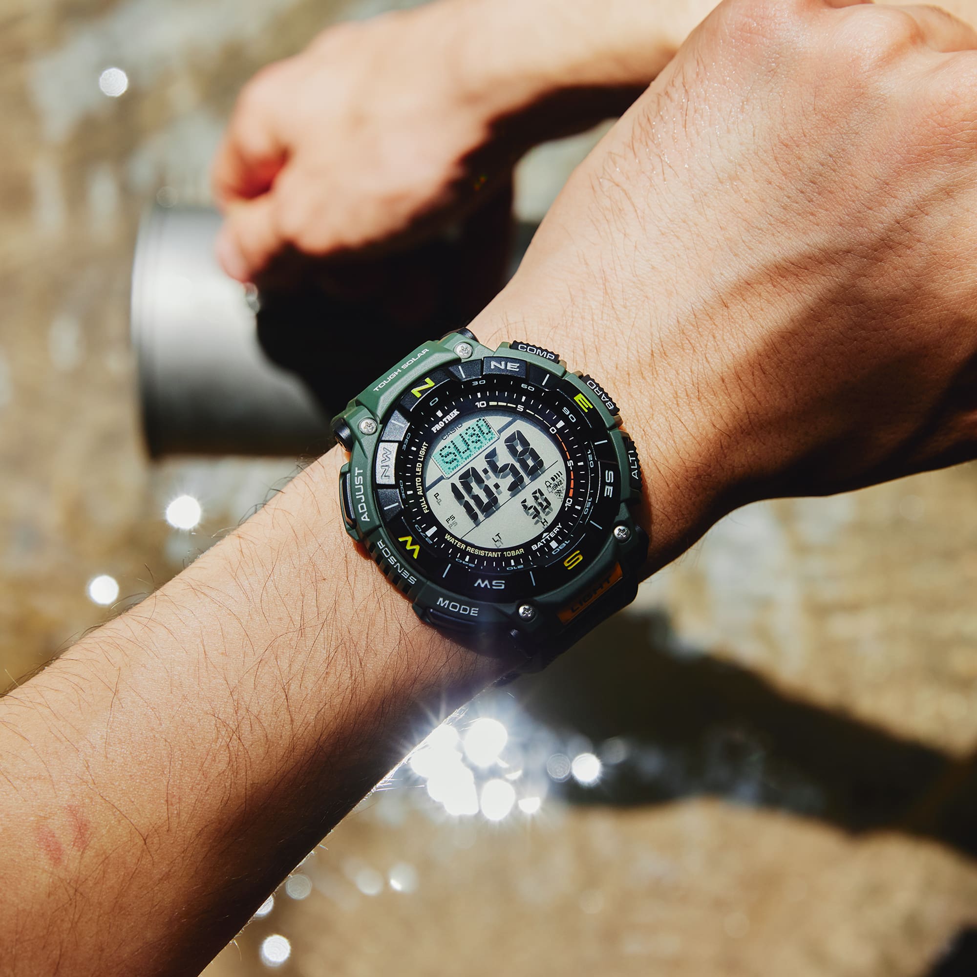 Person wearing a digital wristwatch with a water background