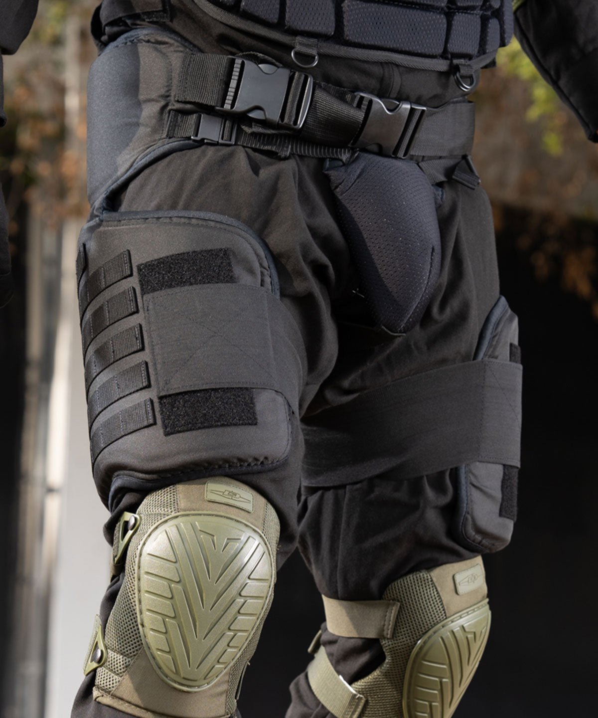 Tactical knee pads and shin guards worn by a person, with a blurred background.
