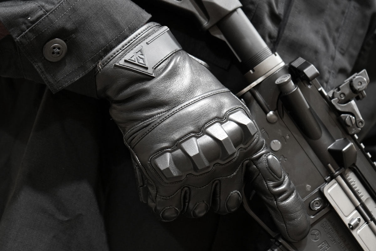 Close-up of Damascus Phenom 6 PG1 hard knuckle gloves gripping a firearm, showing grip