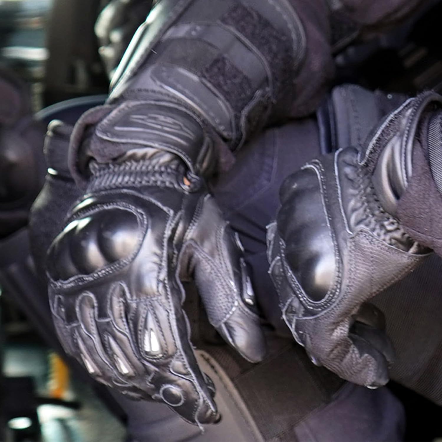 Close-up of a riot police officer wearing black tactical gloves with reinforced knuckle and palm padding, set in a dark, real-world environment.