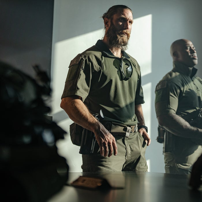 Tactical team members in OD green shirts, showcasing strength and readiness for action in a high-pressure environment.