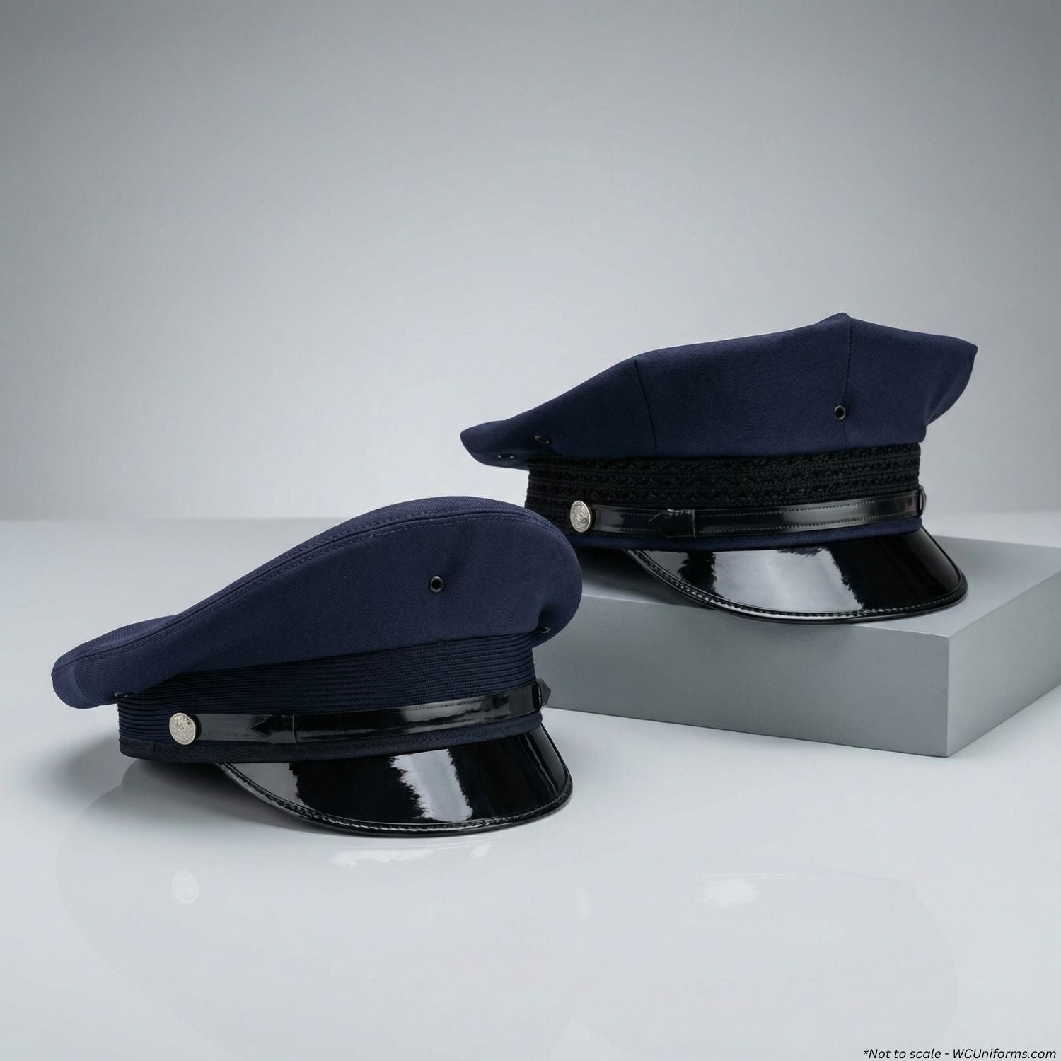 Two navy blue police caps with black visors on a light gray background