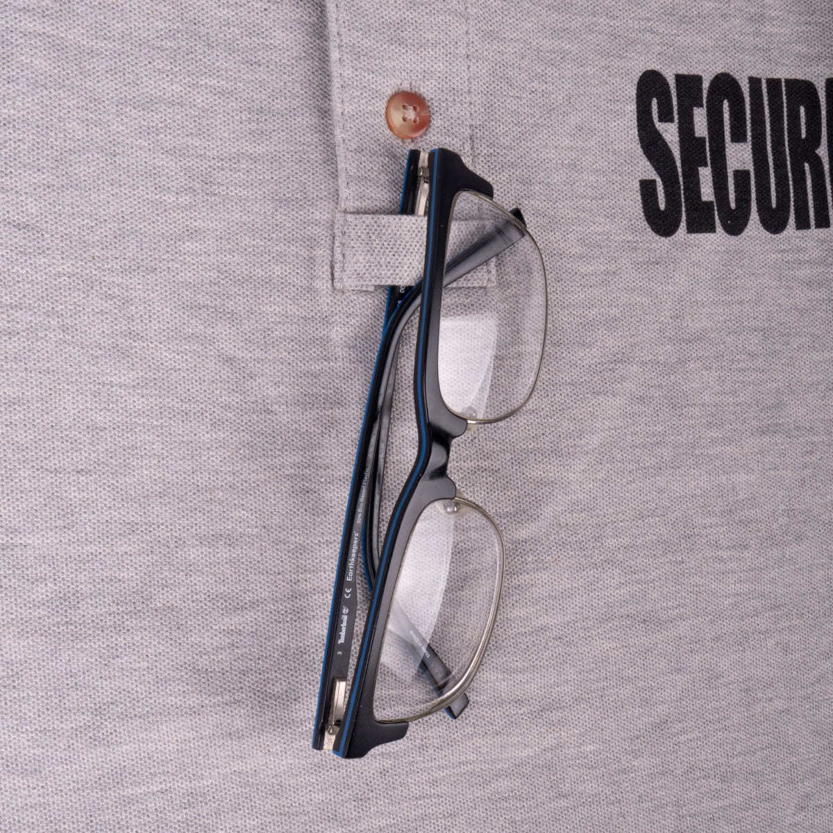 Chest mic or glasses holder with glasses hung beside the SECURITY lettering