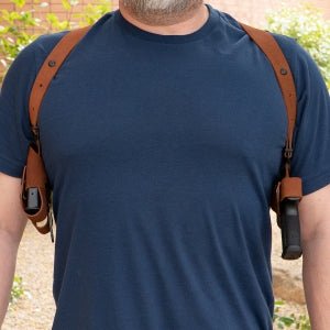 Man wearing a blue t-shirt with a brown leather shoulder holster