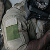 Police officer in tactical gear with a green patch on the shoulder, showcasing durability and functionality in the field.