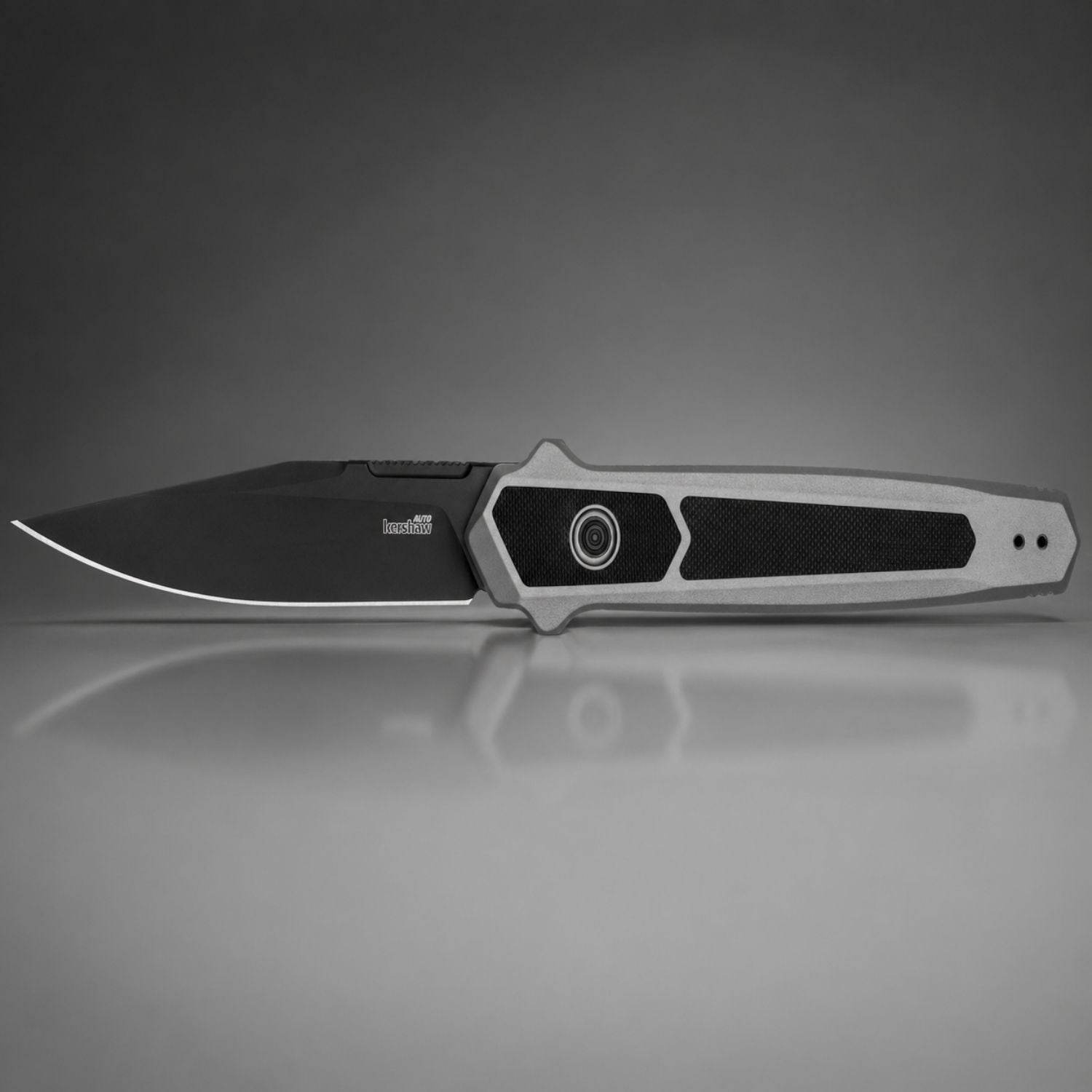 Folding knife with a black blade and gray handle on a reflective gray surface