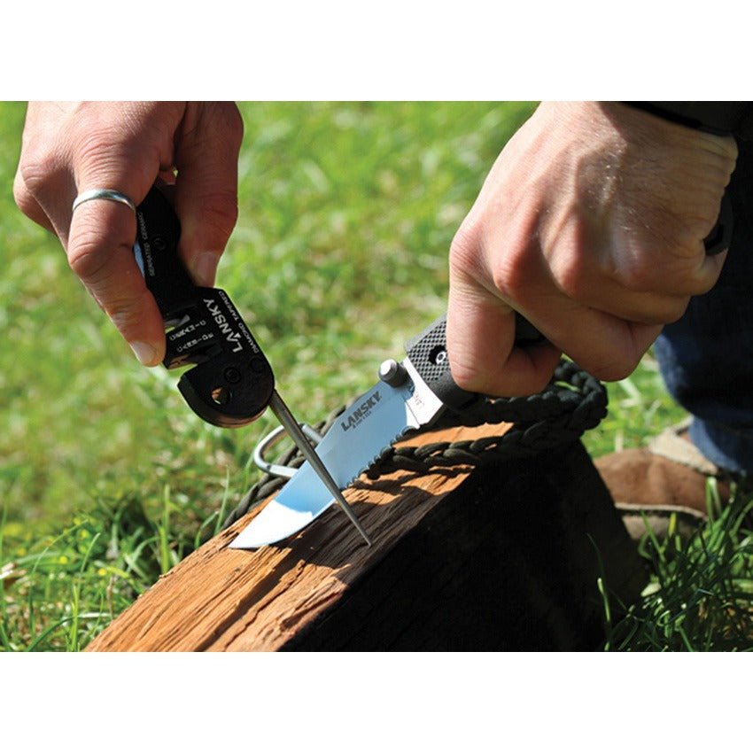 Person using a knife to cut through a piece of wood with grass in the background
