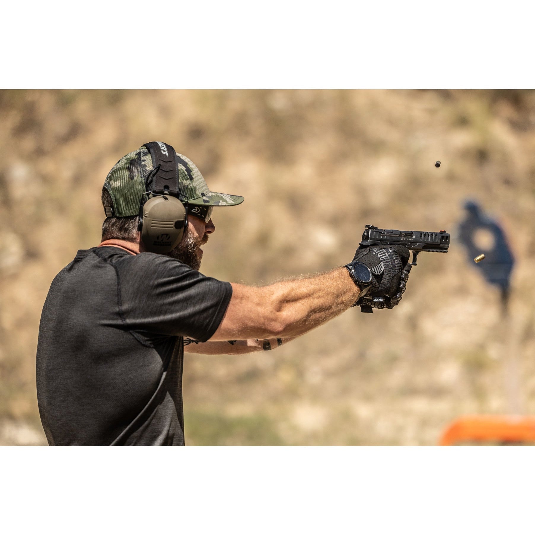 Shooter wearing Mechanix Wear Precision Pro tactical gloves while firing a handgun at an outdoor range