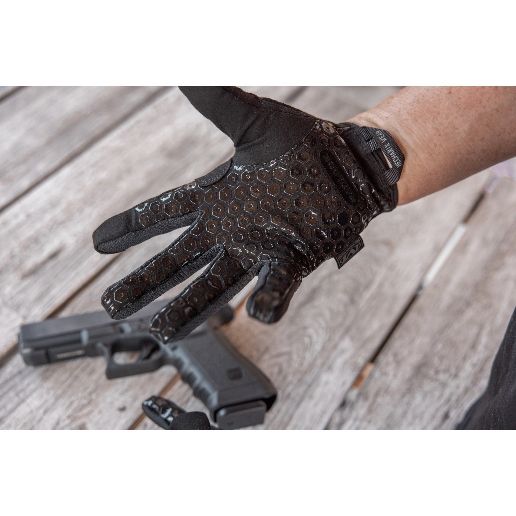 Mechanix Wear Precision Pro glove palm showing the Padlock silicone grip beside a handgun