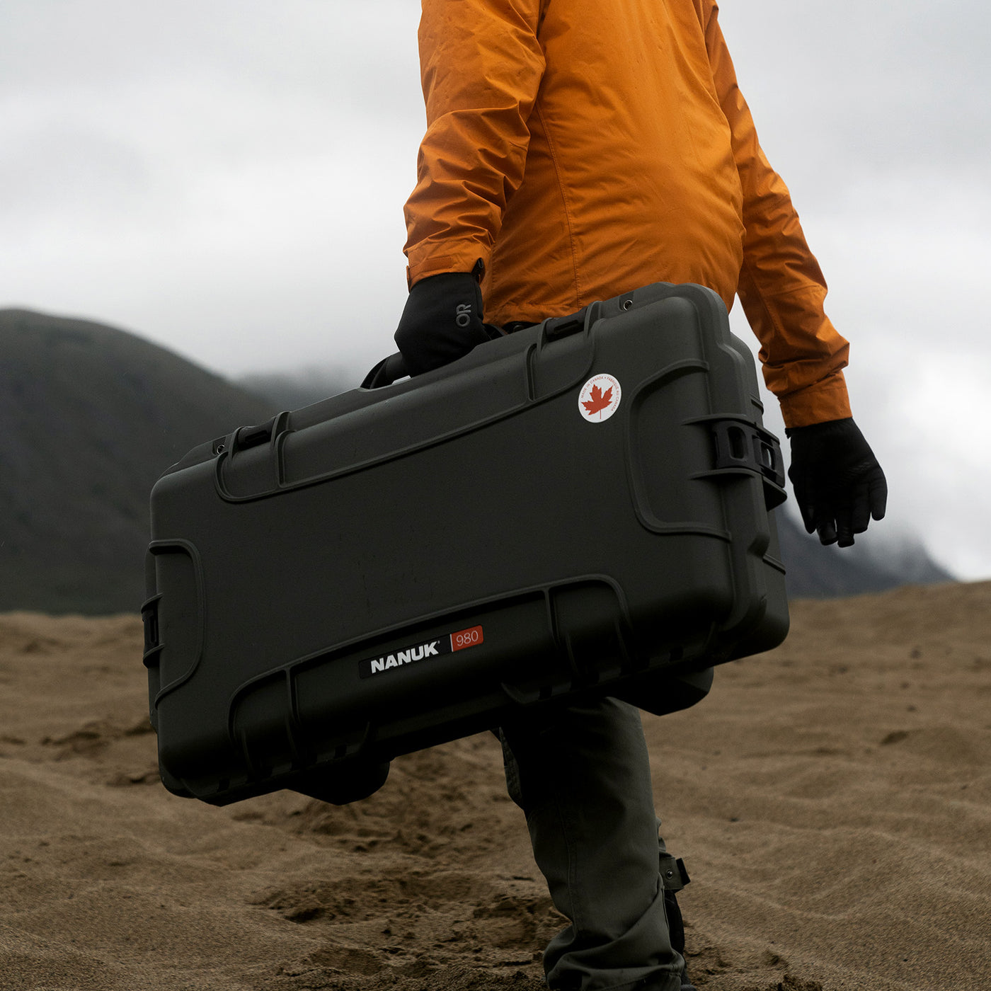 Person holding a black Nanuk case in a desert landscape