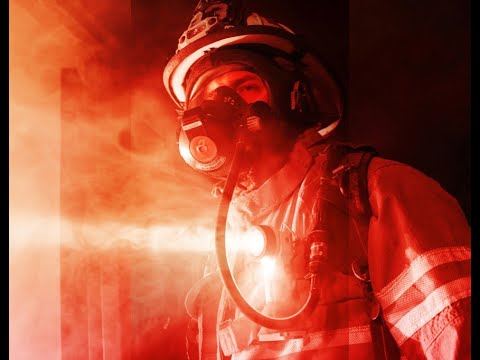 Firefighter in full gear with a red hue in a smoke-filled environment