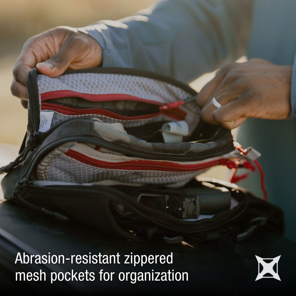 Person organizing items in a black mesh bag with text about abrasion-resistant zipped pockets.