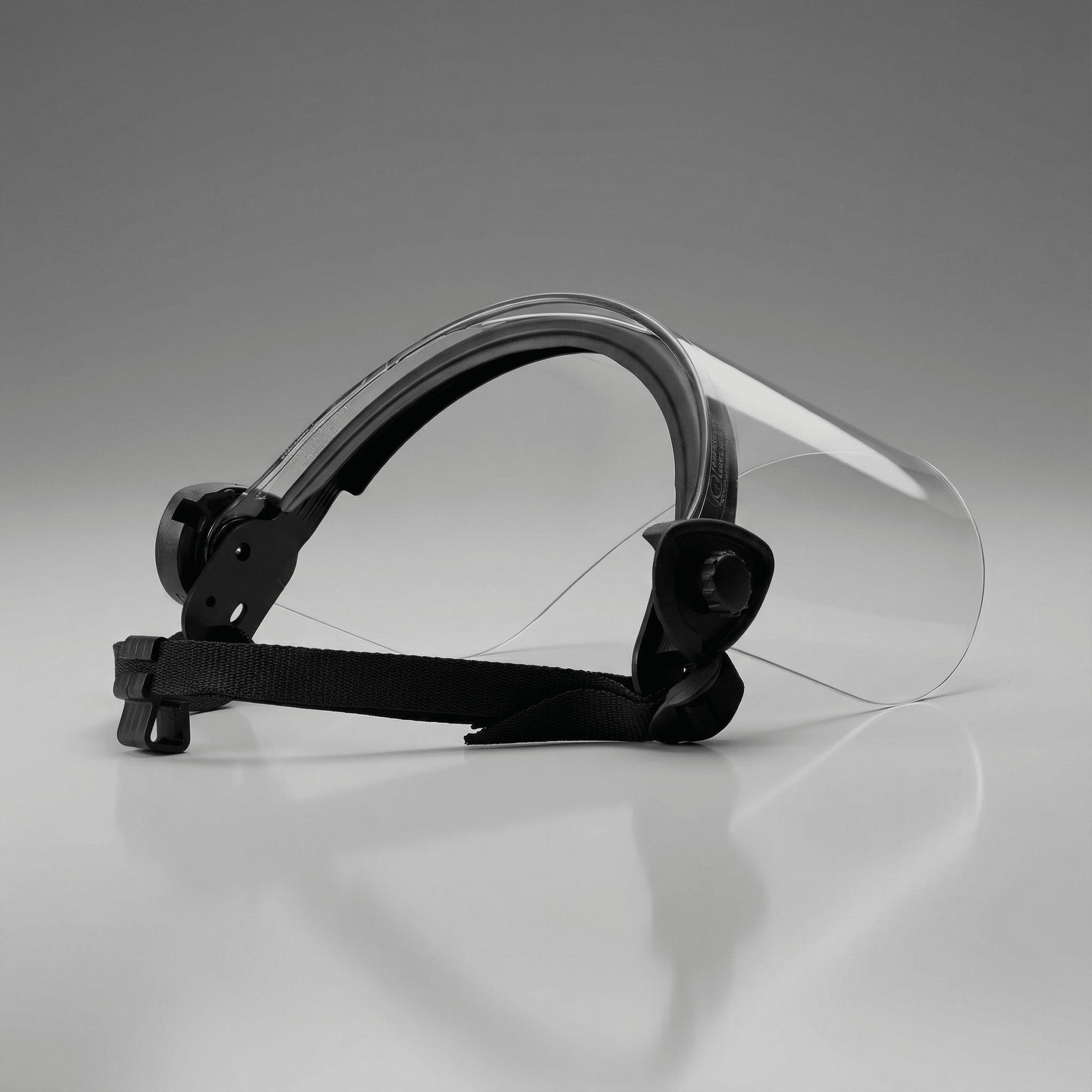 Clear face shield with black headband on a gray background