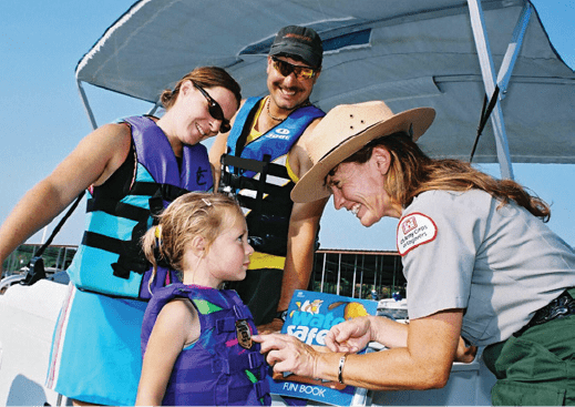 Woman and child with life vests being checked by a park ranger at a boat launch.