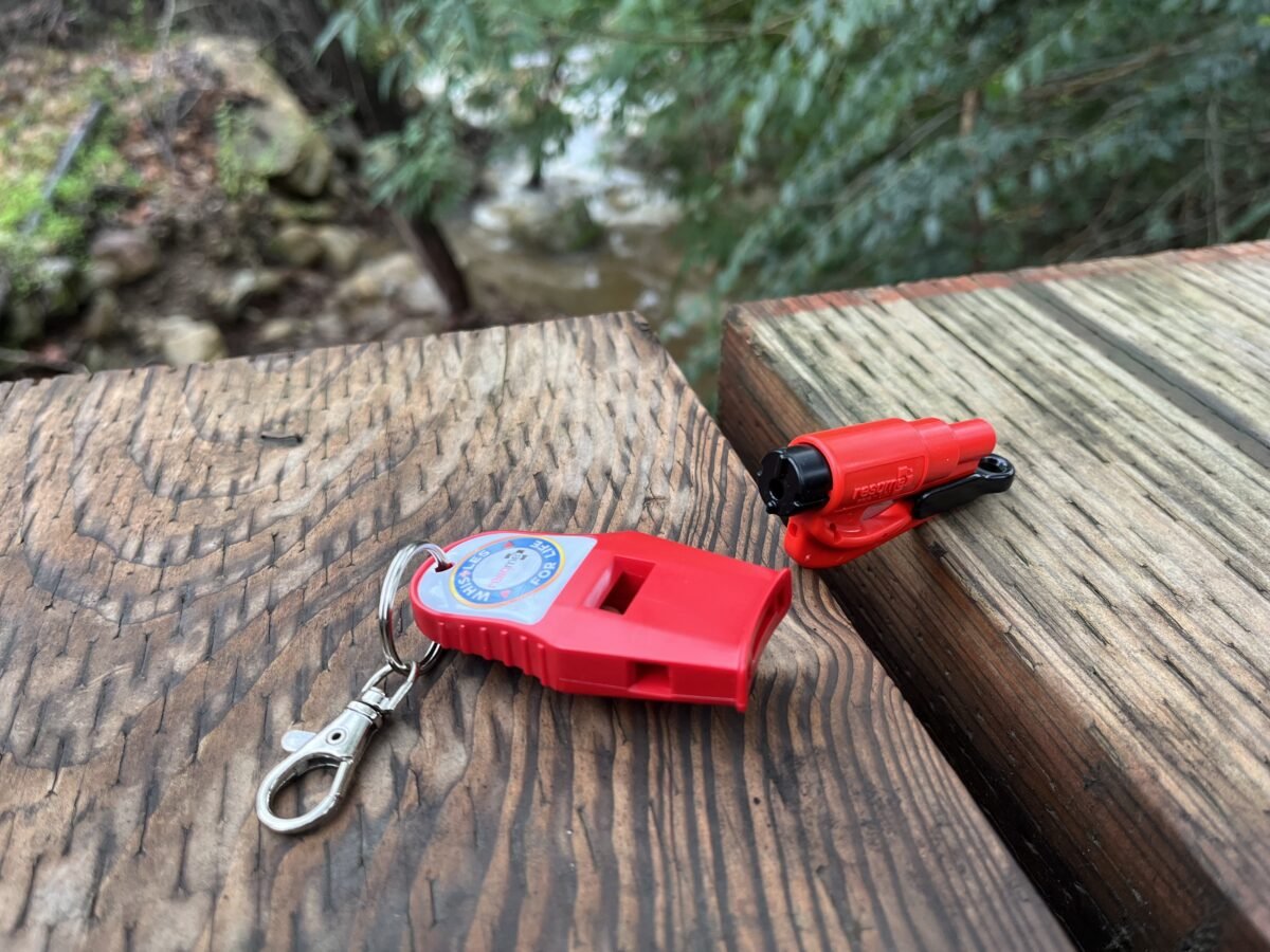 Two red whistles on a wooden surface with a natural background