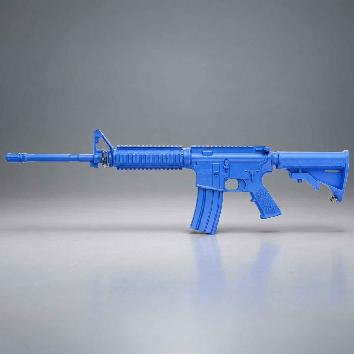 Blue Ring's BlueGuns M4 FSM4FTRCS training rifle with flat top, closed stock and forward rail, side view on gray studio background.