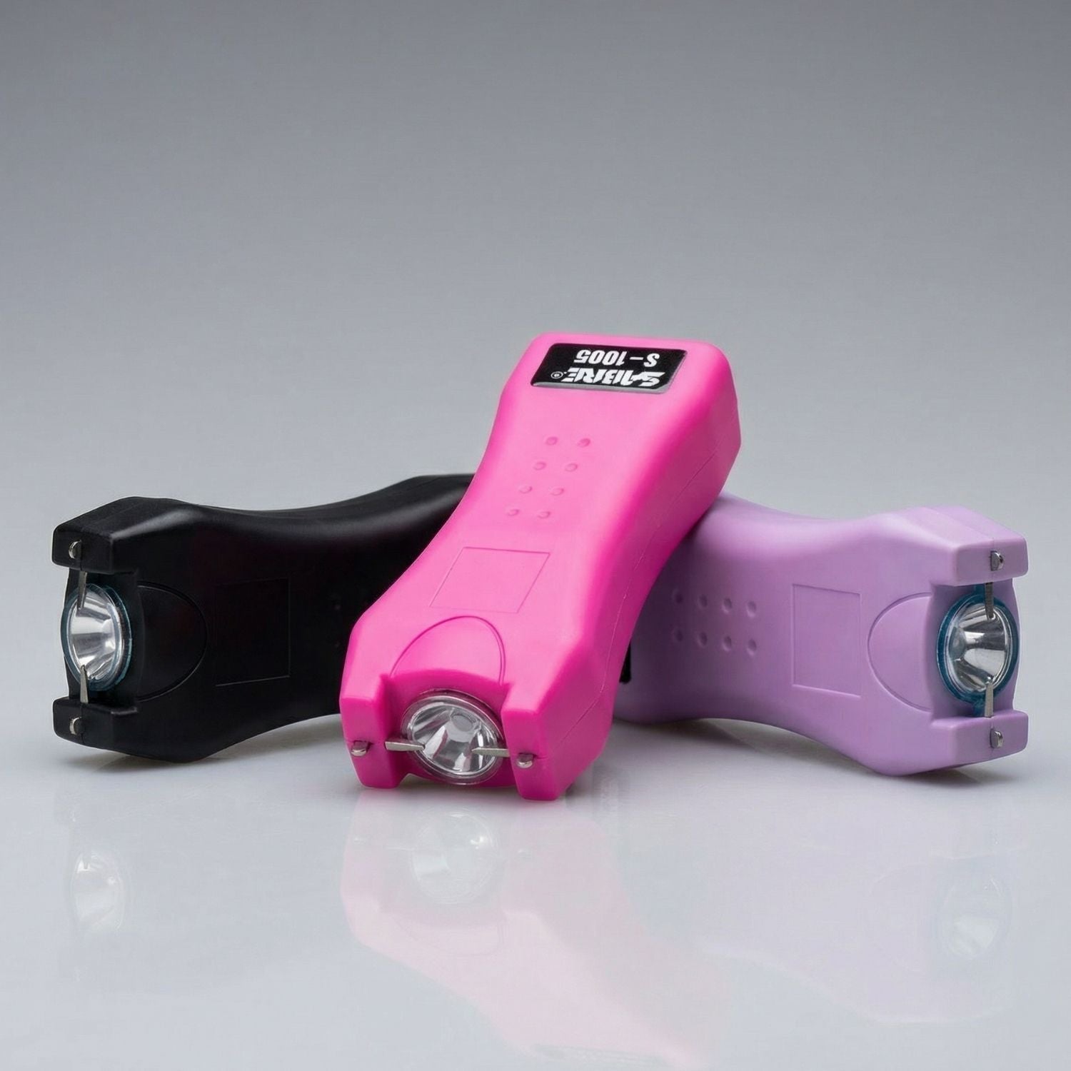 Three stun guns in black, pink, and purple on a gray background