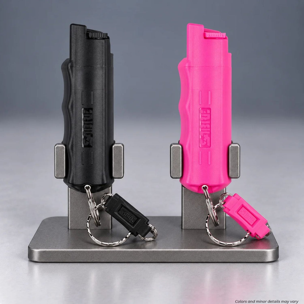SABRE pepper spray keychains HC-14-BK-US-02 in black and HC-NBCF-02 in pink on a display stand with quick release rings