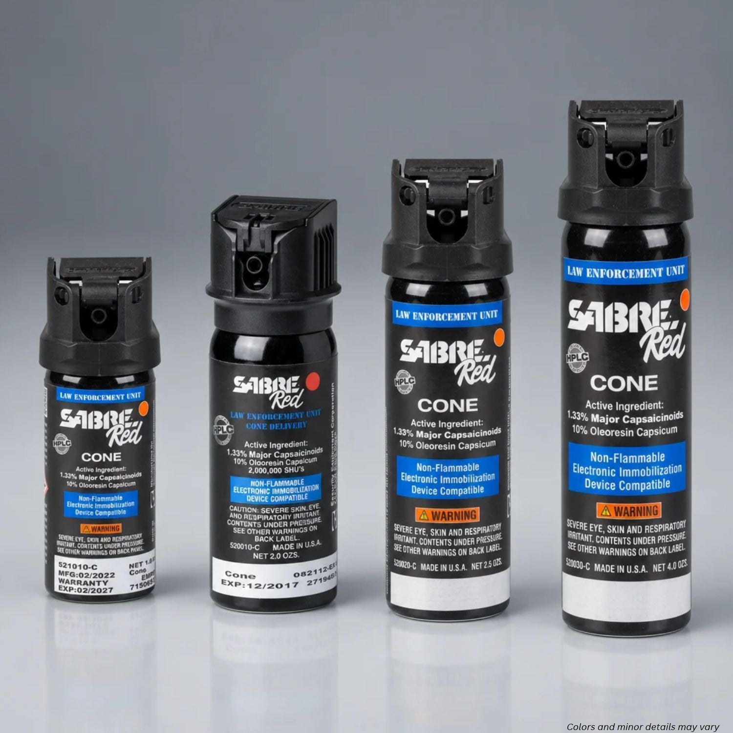 Four Sabre Red pepper spray canisters in different sizes arranged in ascending order from left to right on a reflective gray surface against a gradient gray background.