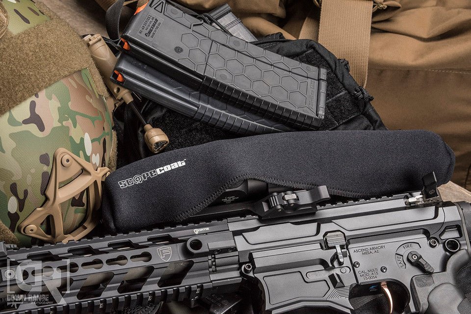 Black rifle with magazine and tactical gear on a camouflage surface