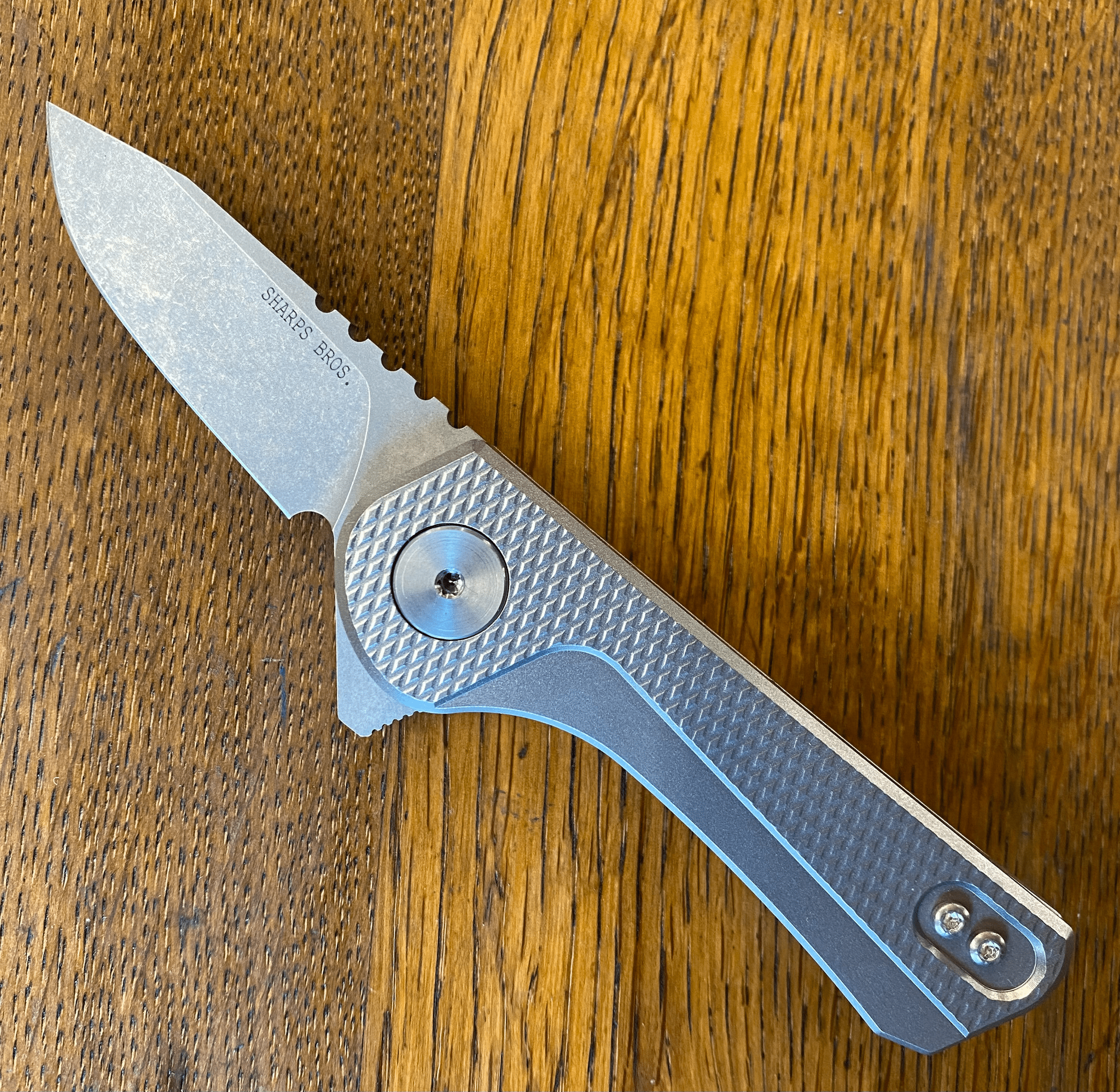 Sharps Bros Meanstreak folding knife with sleek design and CPM MagnaCut blade on wooden surface.
