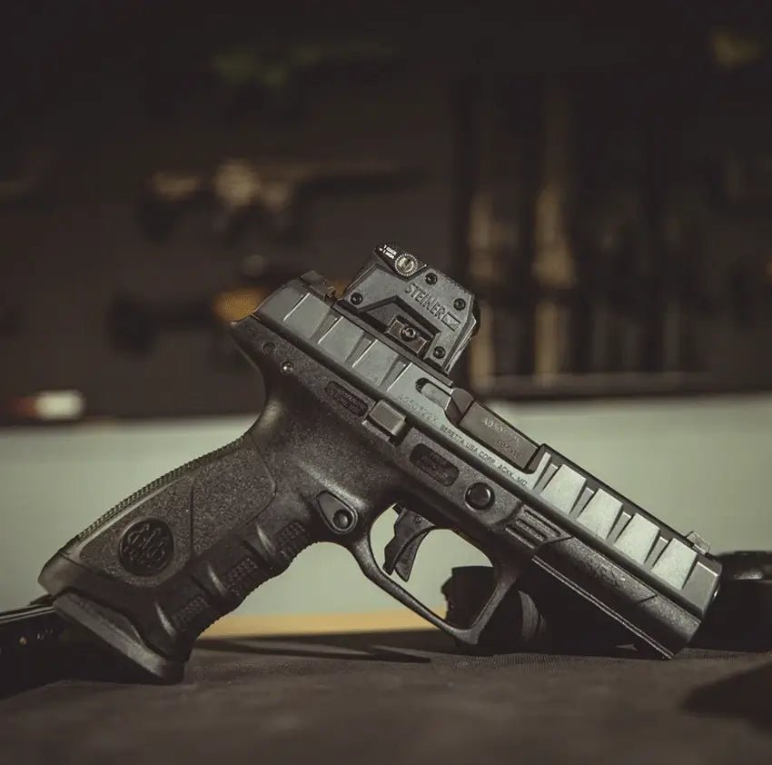 Black handgun with a mounted device on a blurred background