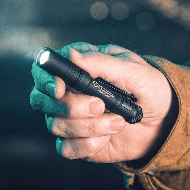 Black Streamlight MicroStream USB flashlight held in one hand with the light on