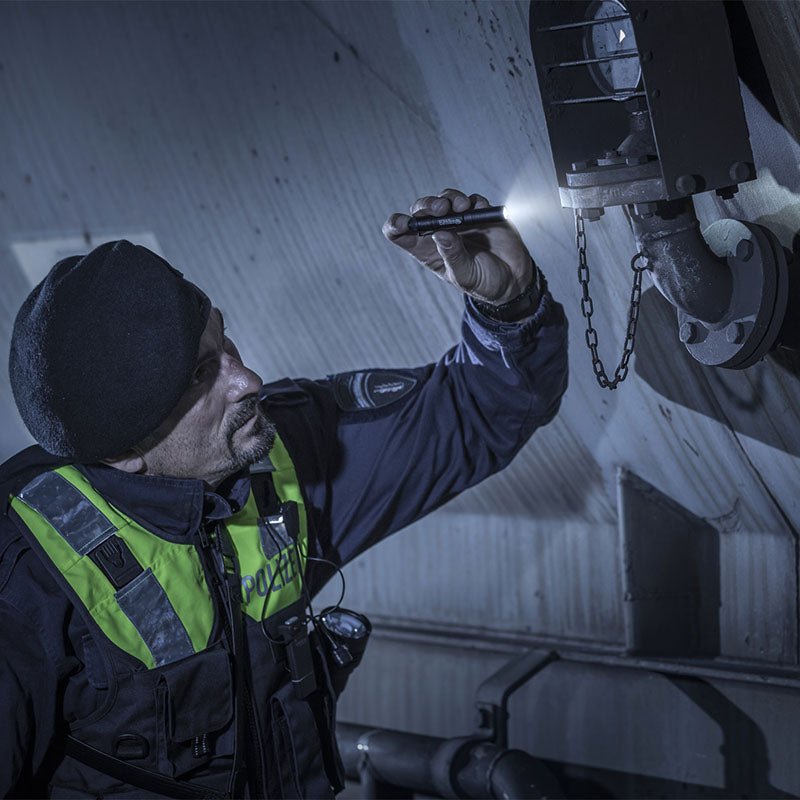 Police officer using a Streamlight MicroStream USB to inspect industrial equipment