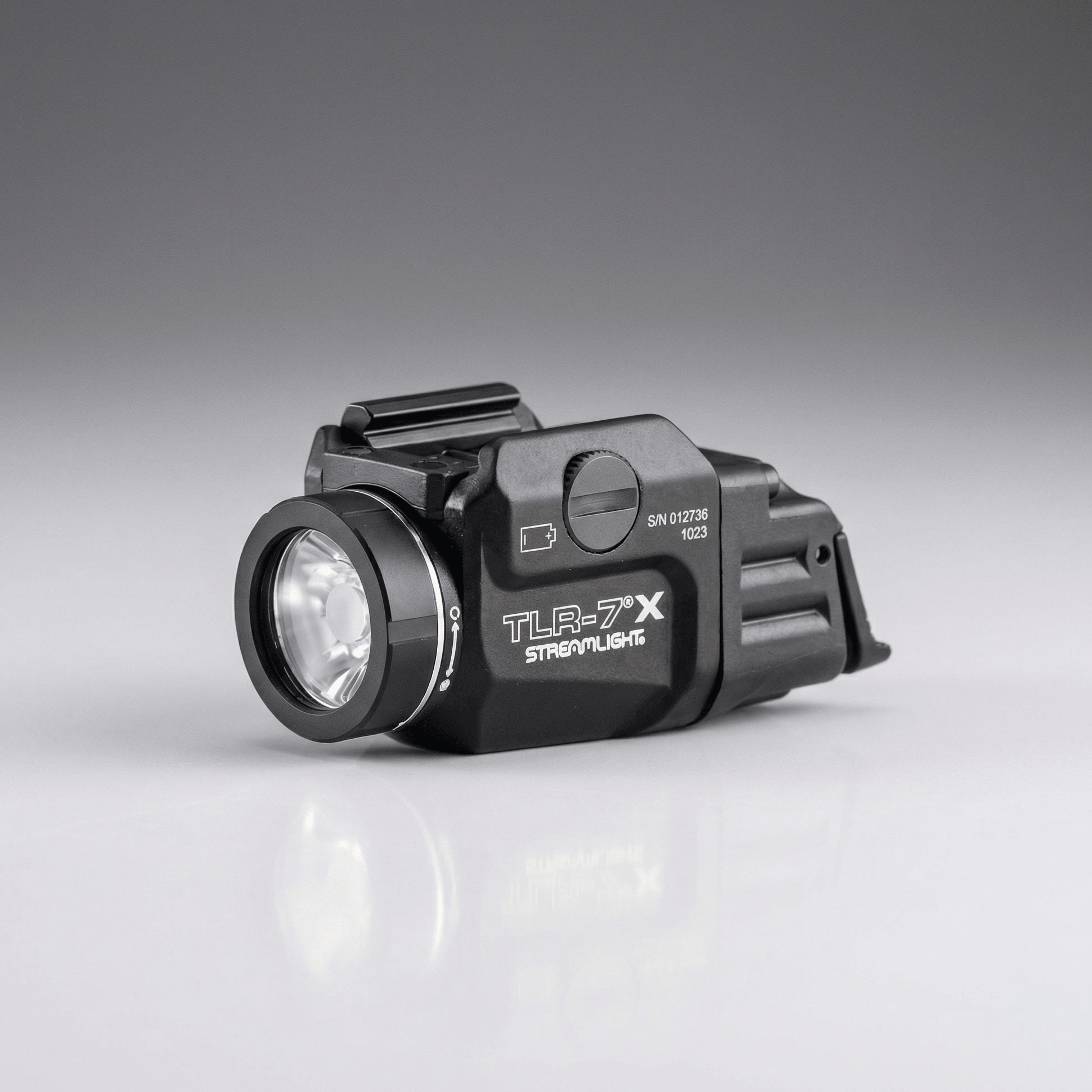 Black tactical flashlight with 'TLR-7X' branding on a gray background