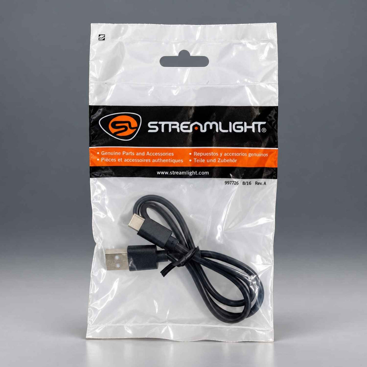 A Streamlight USB cable inside its original clear plastic packaging with a black and orange brand label, set against a neutral gray background.