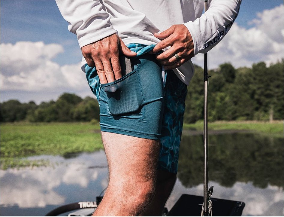Person fishing on a boat with green shorts and a white shirt.