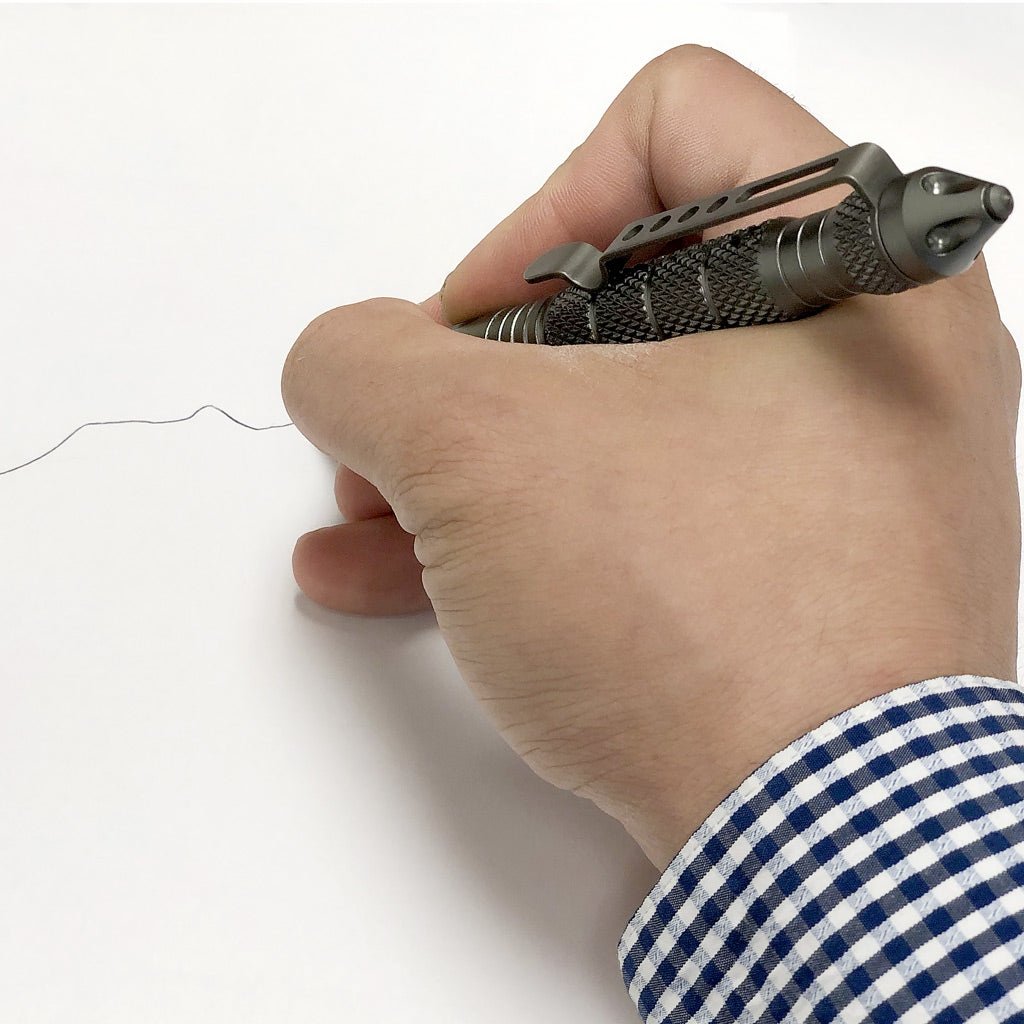 Gunmetal gray UZI Tactical Defender Pen writing with its ballpoint tip