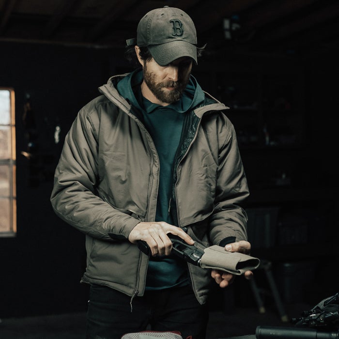 Man in outdoor setting holding a handgun and holster