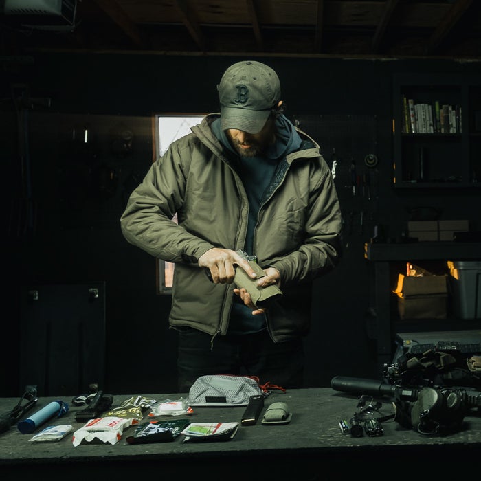 Person in a dimly lit room organizing items on a table with various equipment.