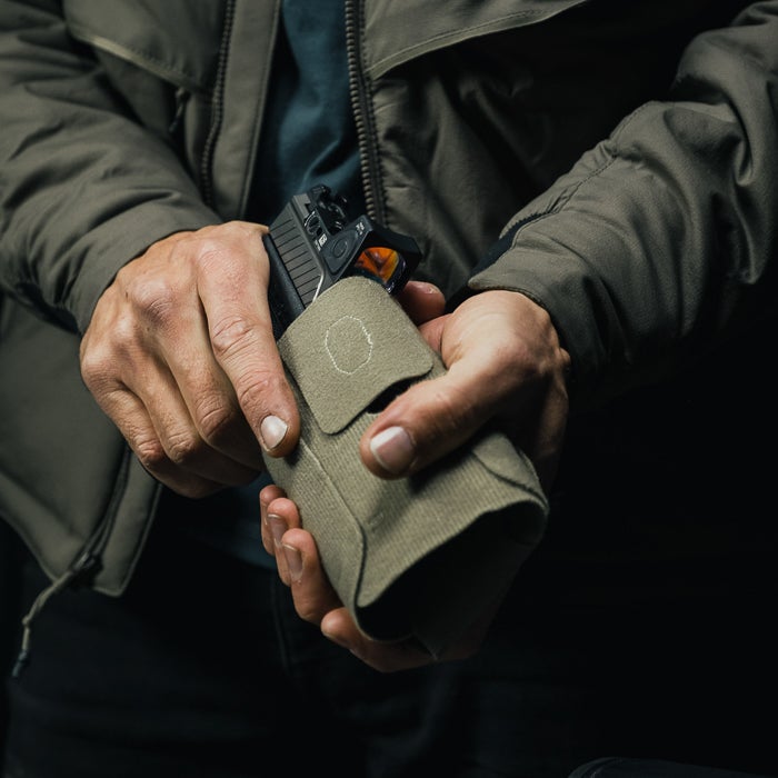 Person holding a green tactical magazine in a dark setting