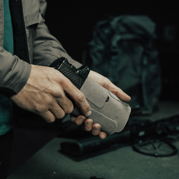 Person holding a gun in a green holster with a blurred background