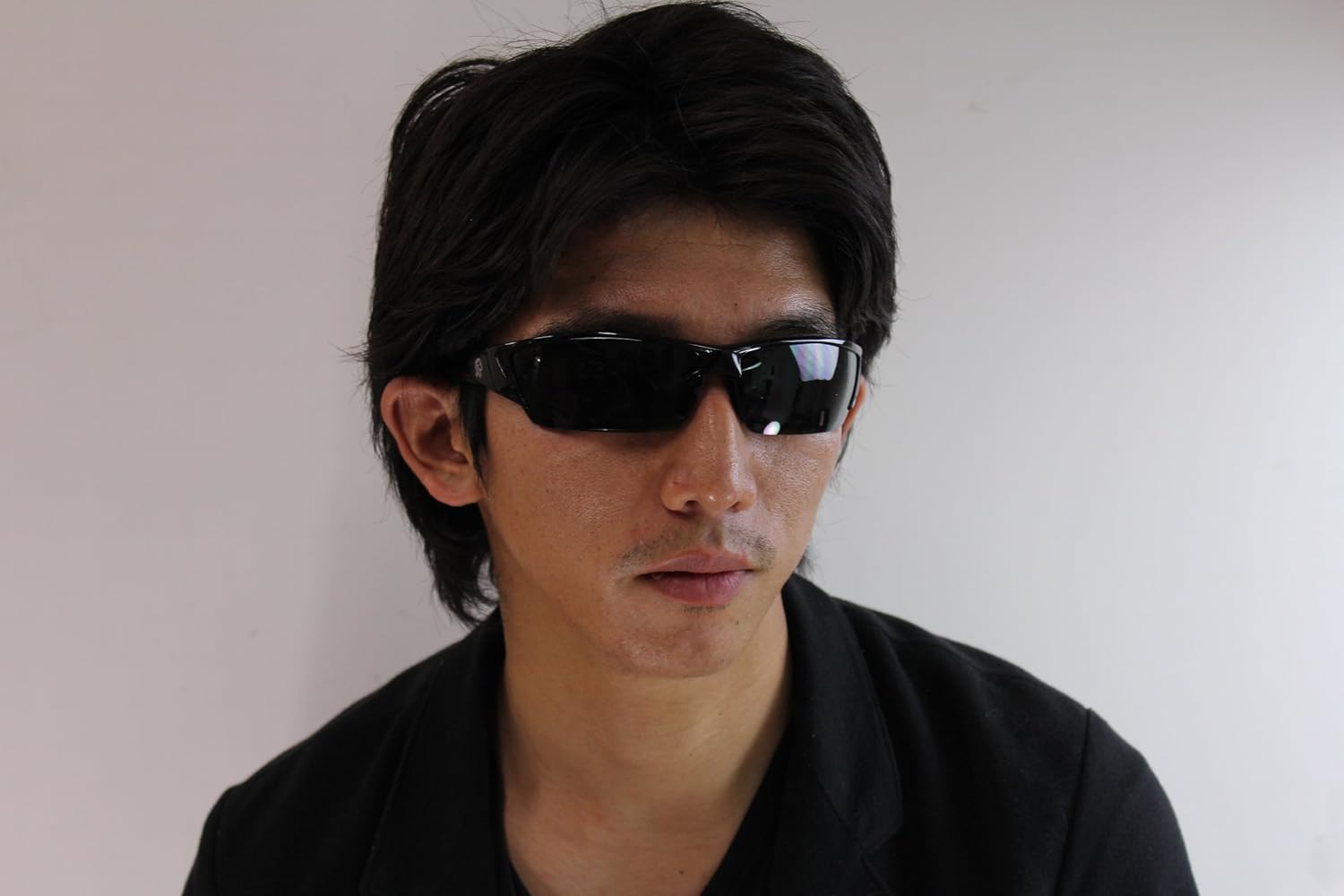Person wearing black sunglasses against a plain background