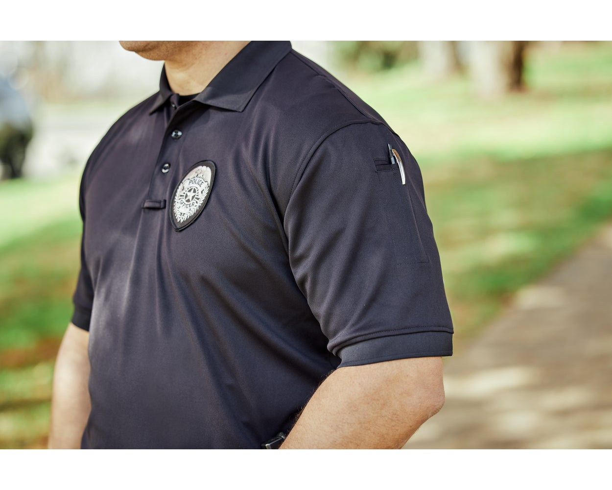 Officer wearing the navy Flying Cross Impact Polo with a badge and a pen in the sleeve pocket