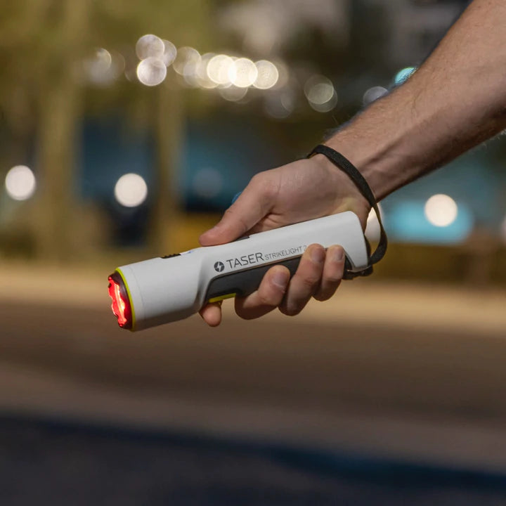 TASER StrikeLight 2 white stun flashlight held in hand, demonstrating grip and size